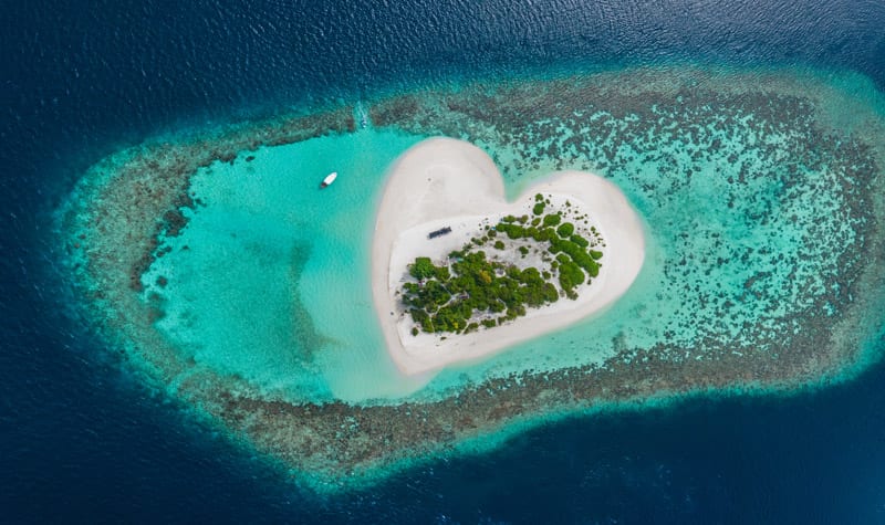 Drone Aerial view of tropical heart shaped island at Maldives paradise
