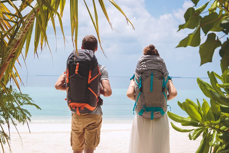 Boy and girl with backpacks island hopping in the Maldives