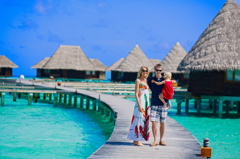 Family walking on bridge towards to water bungalows at the Maldives