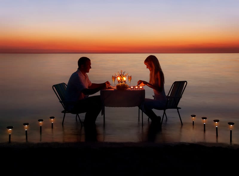 Loving couple share a romantic dinner at sea beach in the Maldives