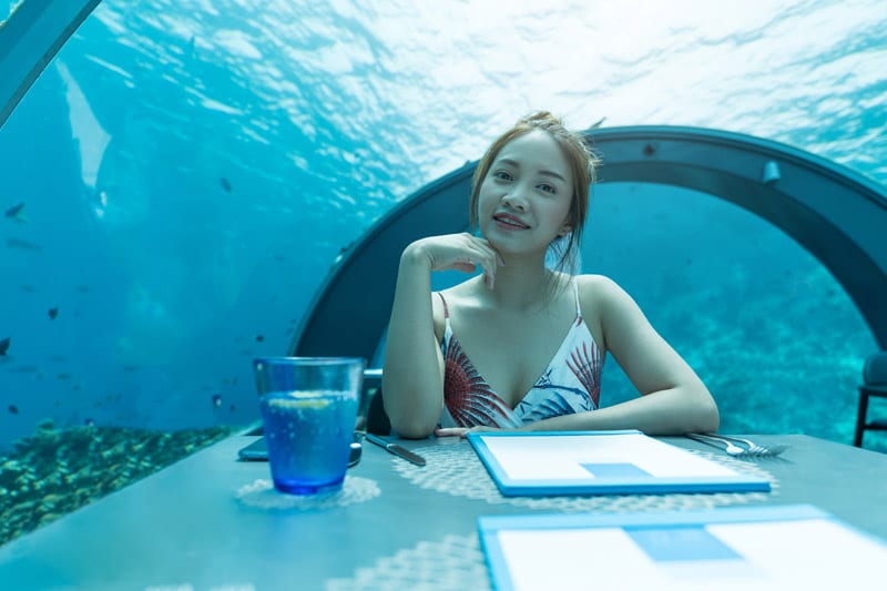 Woman sitting at a table in a undersea restaurant in the Maldives