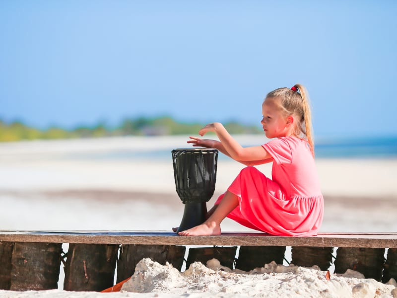 A child plays with drums on the beach