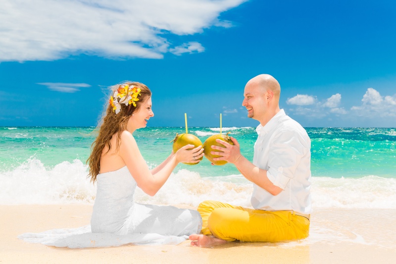 bride and groom drinking coconut water on beach